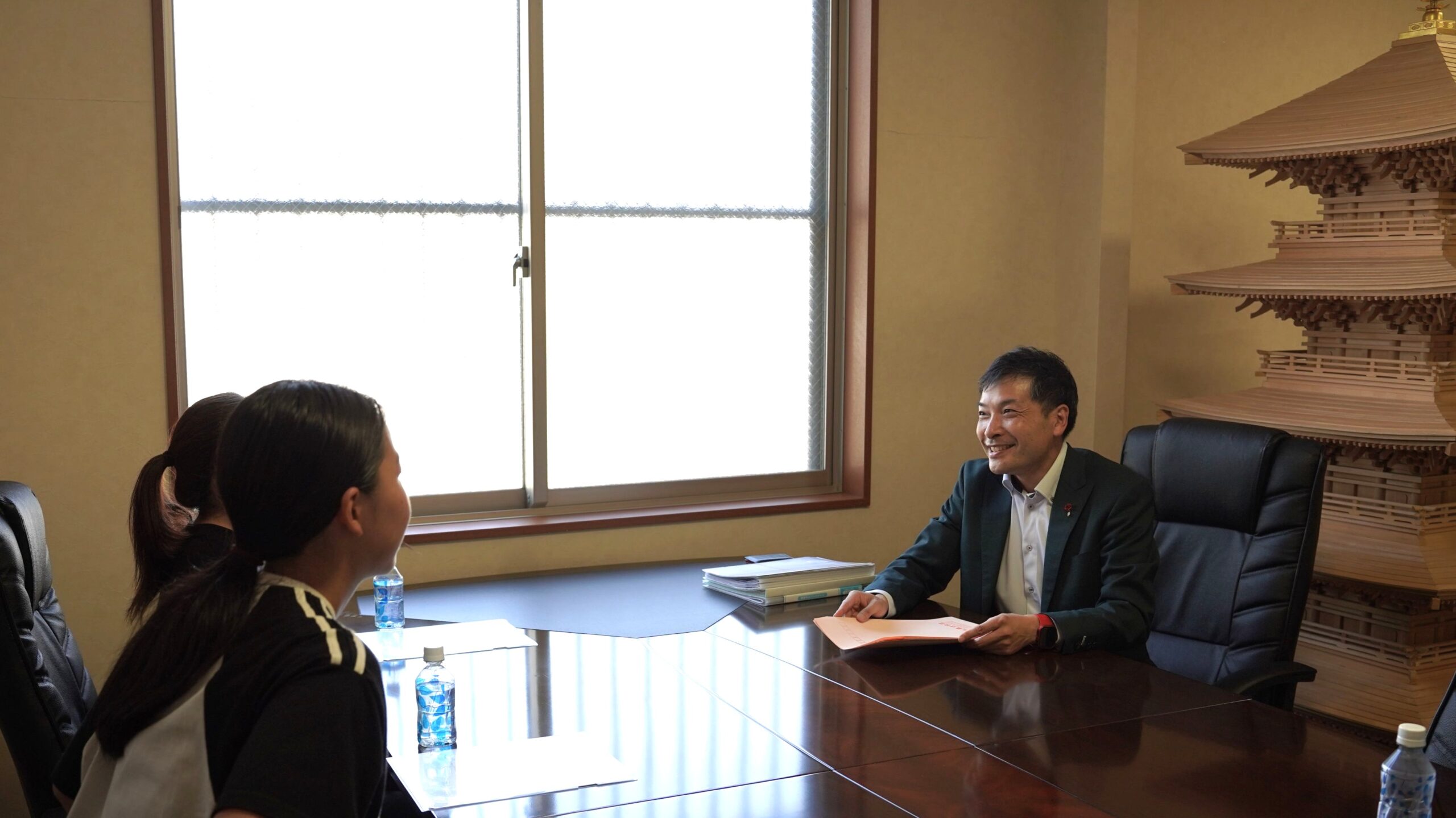 アイデアル株式会社・徳永代表(右)が、学生記者(左・背)からのインタビューに笑顔で答える様子。地域活動や企業の想いを熱弁。